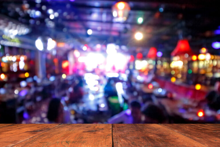 Wooden table in front of abstract blurred background of resturant lights