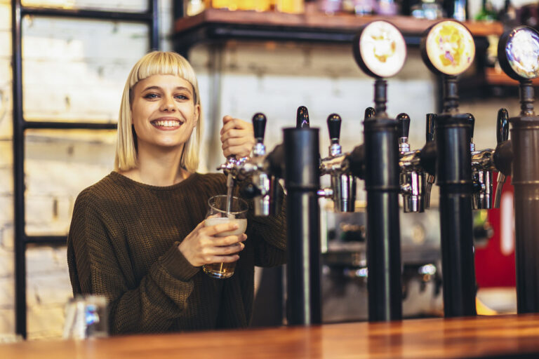 Female bartender tapping beer in bar.